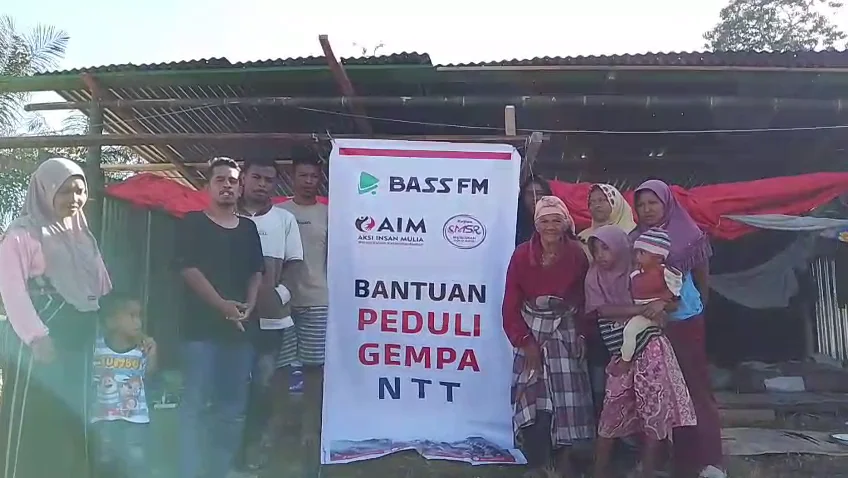 Warga dan relawan berfoto bersama di samping spanduk Bantuan Peduli Gempa NTT dari BASS FM dan AIM